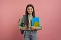 Portrait of happy young female student with backpack and books posing over pink studio background Royalty Free Stock Photo