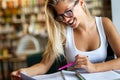 Portrait of happy young female student taking notes from a book at college library. Royalty Free Stock Photo