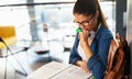 Portrait of happy young female student taking notes from a book at college library. Royalty Free Stock Photo