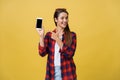 Portrait of a happy young girl dressed in summer pointing finger at blank screen mobile phone isolated over yellow Royalty Free Stock Photo