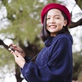 Portrait happy young girl use mobile phone wear sweater and red hat on nature background Royalty Free Stock Photo