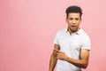 Portrait of happy young good-looking tan-skinned male student with afro hairstyle in casual smiling, pointing aside with finger, Royalty Free Stock Photo
