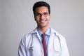 Portrait of happy young handsome Indian man doctor smiling