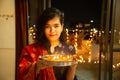 Portrait of Happy Young indian gorgeous woman hold plate/thali with diya/clay oil lamps wearing traditional dress,celebrating Royalty Free Stock Photo