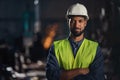 Portrait of happy young industrial man with protective wear indoors in metal workshop, looking at camera.