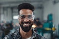 Portrait of happy young industrial man working indoors in metal workshop, looking at camera.