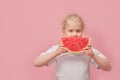 portrait happy young little girl is holding slice of watermelon over colorful pink background Royalty Free Stock Photo