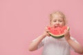 portrait happy young little girl is holding slice of watermelon over colorful pink background Royalty Free Stock Photo