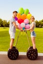 Portrait of happy young lovers with balloons using segway in park Royalty Free Stock Photo