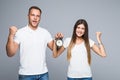 Portrait of happy young loving couple holding alarm clock make winner gesture isolated on gray background Royalty Free Stock Photo