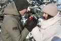 Portrait of happy young loving couple in winter forest. Guy warms his girlfriends hands