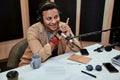 Portrait of happy young male radio host smiling while talking, broadcasting in studio using microphone and headphones Royalty Free Stock Photo