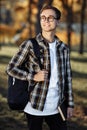 Portrait of happy young male student with glasses in casual outfit holding backpack and posing at the park Royalty Free Stock Photo