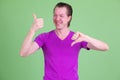 Portrait of happy young man choosing between thumbs up and thumbs down Royalty Free Stock Photo