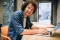 Portrait of happy young man with curly hair using laptop for working and browsing online. Smart Caucasian male reading news, Royalty Free Stock Photo