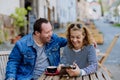 Portrait of happy young man with Down syndrome with his mother sitting at cafe outdoors and talking. Royalty Free Stock Photo