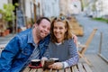 Portrait of happy young man with Down syndrome with his mother sitting at cafe outdoors and talking. Royalty Free Stock Photo