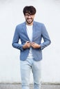 Happy young man with glasses standing abasing white wall