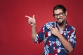Portrait of a happy young man in Hawaiian shirt pointing sideways.