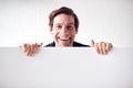 Portrait Of Happy Young Man Holding Blank White Card With Copy Space Standing Against White Wall Royalty Free Stock Photo