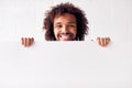 Portrait Of Happy Young Man Holding Blank White Card With Copy Space Standing Against White Wall Royalty Free Stock Photo