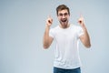 Portrait of a happy young man pointing fingers up at copy space isolated over gray background. Royalty Free Stock Photo