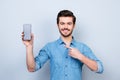 Portrait of happy young man pointing with his finger on the screen of his smartphone on light blue background Royalty Free Stock Photo