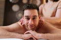 Portrait of happy young man relaxing with oil massage on back at spa resort looking at camera. Closeup face of handsome Royalty Free Stock Photo