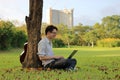 Portrait of happy young man is smiling with a laptop computer in city park. Royalty Free Stock Photo