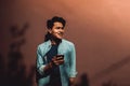 Portrait of a Happy Young Man Smiling while Using Mobile Phone. Lifestyle of Modern People. Standing by the Colorful Wall on Hot Royalty Free Stock Photo