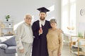 Man student in graduate gown and diploma in hands standing with senior old parents at home