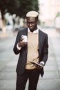 Portrait of a happy young man in suit walking and reading text message on his mobile phone in the city street Royalty Free Stock Photo