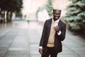 Portrait of a happy young man in suit walking and reading text message on his mobile phone in the city street Royalty Free Stock Photo