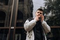 Portrait of happy young man walking on the street and looking aside while talking by his phone Royalty Free Stock Photo