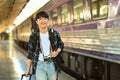 Portrait of happy young man walking in a train station with with suitcase. Traveling and vacations concept Royalty Free Stock Photo