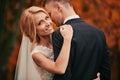 Portrait of Happy young married couple in golden yellow fall autumn park. beautiful bride and stylish groom hugging in Royalty Free Stock Photo