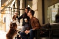 Portrait of happy young man and woman have walk outdoor with their pet, feed it with something delicious, sit on chairs Royalty Free Stock Photo