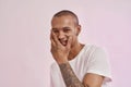 Portrait of happy young mixed race tattooed man in white t shirt smiling at camera, touching his face, posing isolated Royalty Free Stock Photo