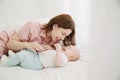 Portrait of happy young mother and baby lying on the bed at home Royalty Free Stock Photo