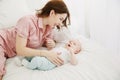 Portrait of happy young mother and baby lying on the bed at home Royalty Free Stock Photo