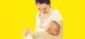 Portrait of happy young mother breastfeeding her baby on yellow background Royalty Free Stock Photo