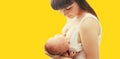 Portrait of happy young mother breastfeeding her baby on yellow background Royalty Free Stock Photo