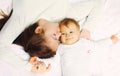 Portrait of happy young mother and cute baby lying on the bed at home together Royalty Free Stock Photo