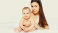 Portrait of happy young mother and cute baby lying on the bed at home together on white background Royalty Free Stock Photo