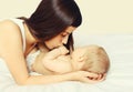 Portrait of happy young mother and cute baby lying on the bed at home together on white background Royalty Free Stock Photo