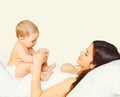 Portrait of happy young mother and cute baby lying on the bed at home together on white background Royalty Free Stock Photo