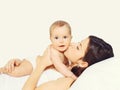 Portrait of happy young mother and cute baby lying on the bed at home together on white background Royalty Free Stock Photo