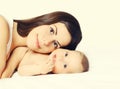 Portrait of happy young mother and cute baby lying on the bed at home together on white background Royalty Free Stock Photo