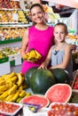 Mother with girl picking bananas on market . Royalty Free Stock Photo