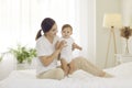 Portrait of a happy young mother together with her cute baby boy on the bed at home Royalty Free Stock Photo